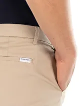 Pantalón de vestir color beige, corte slim, con cierre de botón y cremallera.
