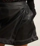 Short pollera negro de cuero sintético con diseño cruzado y costuras contrastantes.