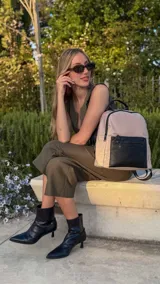 Mochila urbana color gris con detalles en cuero sintético negro. Cuenta con un compartimento principal amplio y un bolsillo frontal con cierre.