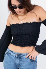 Top color beige, con escote off-shoulder con elástico y mangas largas acampanadas.