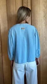 Camisa de mangas largas abullonadas con puños elásticos, cuello redondo y cierre frontal con botones.