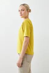 Remera color verde pistacho, de corte recto y manga corta raglán con detalle de vainillas en los hombros.