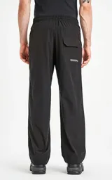 Pantalón negro multifuncional impermeable con elástico en la cintura y los puños, calce regular y bolsillos frontales.