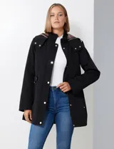 Gabardina impermeable de mujer, color marrón topo, con capucha desmontable y forro interno de abrigo desmontable. Presenta abertura central con cierre oculto y botones a presión, y bolsillos delanteros.