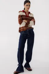 Pantalón de jean azul oscuro de corte recto, con cintura alta con cinturón del mismo material y detalle de flecos en la cintura y en los tobillos.