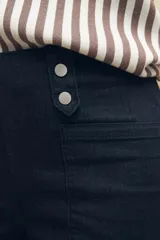 Short de jean negro de tiro alto con detalle de doble botón metálico en la cintura, bolsillos delanteros y traseros.