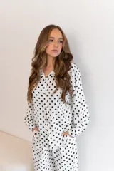Camisa negra con estampado de lunares blancos, de manga larga y cuello clásico.