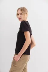 Remera negra de algodón con calce al cuerpo, mangas cortas y cuello redondo. Presenta un bordado frontal de abeja con canutillos dorados y plateados.