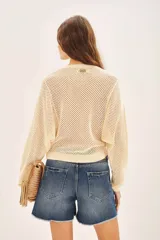 Sweater color crema de algodón con tejido calado y bordado de flores en el hombro.