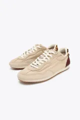 Zapatillas deportivas color beige con detalles en marrón y estampado animal print en el talón. Cierre con cordones y suela de 1,5 cm de altura.
