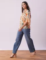 Blusa de gasa estampada con flores color naranja, marca Figueroa & Flower. Tiene cuello a la base, escote en V con lazo, abertura central con botones, delantera plisada y mangas 3/4 amplias.