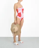 Traje de baño entero de lycra color lila con estampado de flores rojas, con un solo tirante ancho y escote asimétrico.