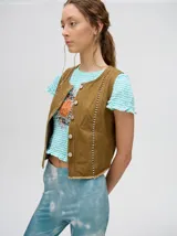 Chaleco marrón de denim con apliques metálicos y flecos en el ruedo.