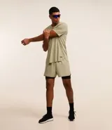 Bermuda deportiva color verde claro con short de compresión interno negro, cintura elástica con cordón ajustable y detalle reflectante trasero.