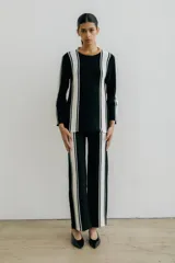 Pantalón de punto color crudo con rayas verticales negras a los costados.