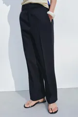 Pantalón de vestir azul marino de lana, con tiro bajo, cintura con trabillas, bolsillos laterales, raya planchada y cierre frontal con cremallera, botón y gancho metálico.