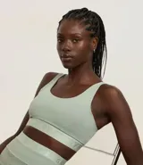 Top deportivo verde claro, confeccionado en microfibra, con breteles anchos fijos, copa y elásticos texturizados con la palabra “GYM” en la parte baja y espalda, sin estampa.