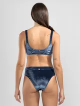 Top de bikini azul de terciopelo con textura a rayas finas, estilo pullover, con copas removibles, detalle metálico cuadrado dorado al frente y dije insignia en la espalda.