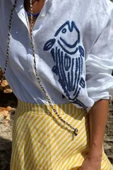 Camisa blanca de lino con bordado de pulpo azul en el pecho, de corte recto y manga larga.