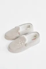 Pantuflas cerradas color beige con interior de piel sintética blanca y detalle de estrellas caladas en el empeine.