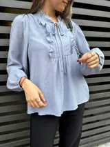 Blusa rosa de mangas largas con puños elásticos, escote en V con volados y lazos.