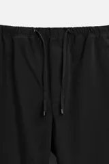 Pantalón de hombre color beige, corte carrot fit, con cintura elástica ajustable con cordón, bolsillos frontales y bolsillo trasero de plastrón.