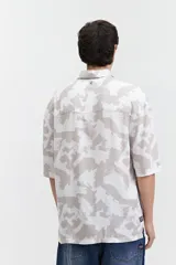 Camisa oversize de manga corta con estampado abstracto en tonos beige y blanco.