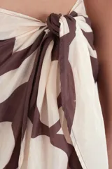 Pareo corto de tela ligera con estampado abstracto en tonos marrones y beige, con amarre lateral.