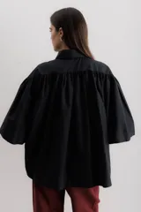 Camisa celeste de algodón con corte amplio, cuello camisero y mangas largas con puños abullonados.
