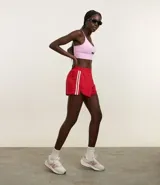 Short deportivo femenino modelo runner, color rojo con cintura elástica y rayas laterales blancas.