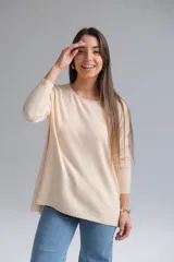 Sweater color beige de corte recto con cuello a la base. La parte delantera es más corta que la trasera y tiene una abertura en la parte baja de la espalda.
