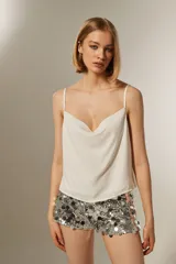 Musculosa blanca de poliéster con breteles finos, cuello drapeado y corte holgado.
