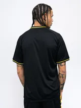 Remera polo negra de poliéster con cuello clásico y mangas cortas. Presenta ribete amarillo en cuello y mangas, escudo del Club Atlético Peñarol bordado en el pecho y corte regular.