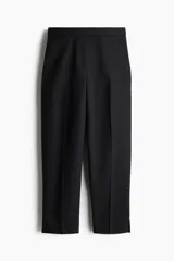 Pantalón cigarette tobillero negro con cintura estándar, cierre y pretina prolongada con corchete oculto. Piernas ajustadas con abertura corta en los bajos, bolsillos al bies y bolsillo de atrás decorativo. Pliegues adelante y atrás.