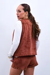 Chaleco marrón de gamuza sintética con apliques de flores y tachas doradas.