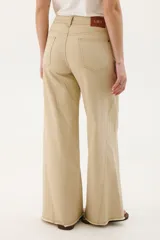 Pantalón de jean acampanado color caramelo con cintura alta y cinturón marrón con tachas.