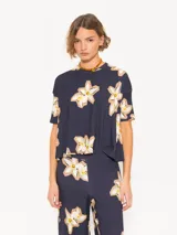 Remera azul marino con estampado de flores blancas y amarillas, de corte holgado, cuello redondo y mangas cortas.