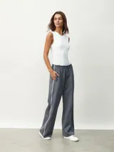 Pantalón deportivo color borgoña, de corte ancho y cintura elástica. Presenta una franja blanca vertical a lo largo de la pierna.