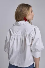 Camisa blanca de mangas 3/4 abullonadas con puños elásticos y cuello clásico.