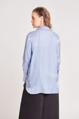 Camisa verde claro de corte recto y mangas largas con puños abotonados. Cierre frontal con botones.