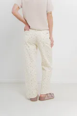 Pantalón de denim color crema con estampado de pequeñas flores rosas y verdes. Corte recto, tiro alto y calce relajado.