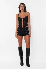 Microshort negro de gabardina elastizada con cierre metálico a la vista en la cartera y bolsillos traseros. En los laterales delanteros presenta cierres metálicos decorativos.