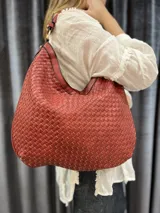 Cartera hobo grande color ladrillo con diseño tejido.