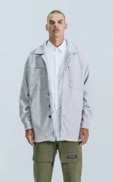 Chaqueta gris melange de paño con cuello clásico, cierre frontal con botones negros, dos bolsillos de parche en el pecho y dos bolsillos laterales.