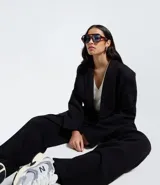 Blazer negro de mujer, modelo largo, con solapas y cierre cruzado de doble botonadura.