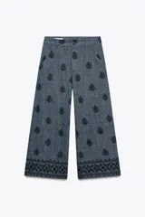 Pantalón culotte de tiro alto con trabillas, bolsillos laterales y traseros. Detalle de bordados combinados a contraste. Cierre frontal con cremallera y botón.