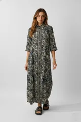 Vestido largo con estampado floral en tonos azul y blanco, corte recto, cuello camisero, manga 3/4 y cierre frontal con botones.