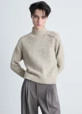Sweater de punto grueso color crema, con cuello perkins y mangas largas.