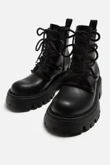 Bota de cuero negra con cordones, cordonera con nueve pasados, tirador trasero y suela track con volumen.