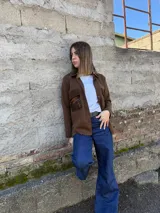Camisa marrón de tejido de punto en lana con bolsillos de cuero y cierre frontal con botones.